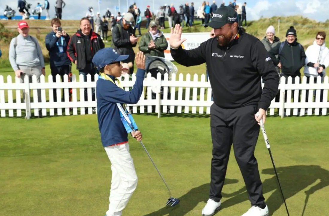 Shane Lowry high-fiving a young golfer on the green at the Irish Open